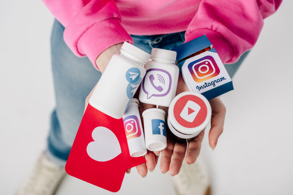 overhead view of girl holding containers with social media logos and red paper cut card with heart symbol on grey background